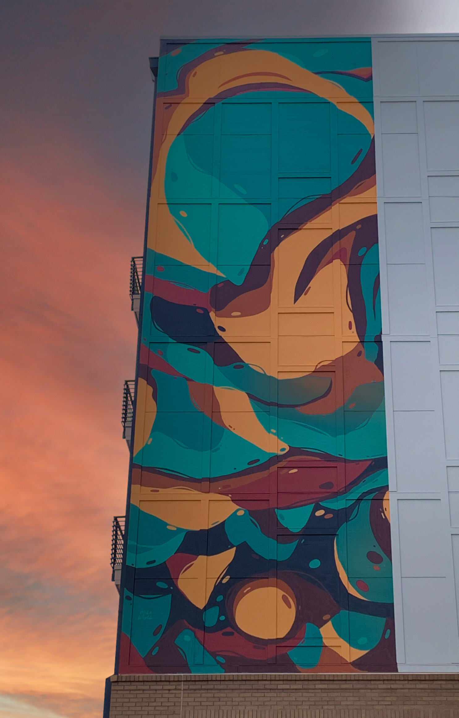 A colorful abstract mural 50 ft high up on the side of a building.